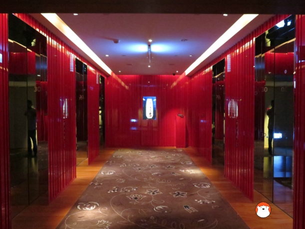 The glssy red elevator-waiting area and the center piece of LCD screen emitting 3D images. 